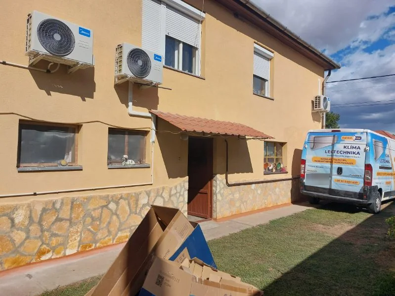 Három Midea kültéri egység egy gesztelyi ház falán, a Comfort Air szerelőautójával